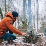 Mężczyzna rozpalający ognisko w trakcie zimowej wyprawy survivalowej